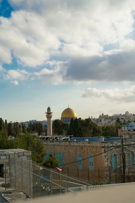 Golden dome mosque with minaret under cloudy sky.